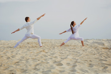  beautiful, athletic couple in white clothes making yoga exercis