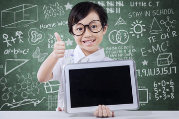 Cute girl shows tablet and thumb up in class