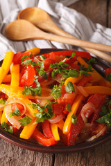 stewed peppers with tomatoes and onions close up on a plate. vertical
