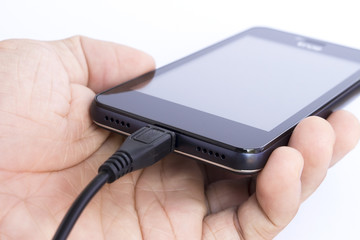 human's hand holding smart phone is charging on white background