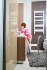 Baby brushing her teeth in the bathroom.