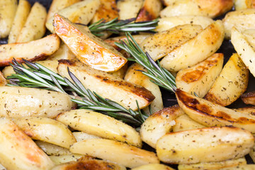Roasted potato wedges with rosemary on a baking tray