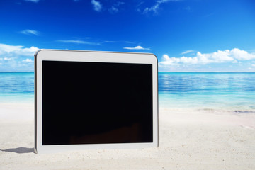 Weisses Tablet mit leerem Touchscreen Display steck im Sand mit einem Seestern am Meeresstrand