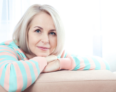 Fototapeta Active beautiful middle-aged woman smiling friendly and looking into the camera at home. Woman's face close up.