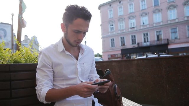 Attractive young man texting. Male in his 20s creating an sms on smartphone. Close-up male hands use phone for making a message. 