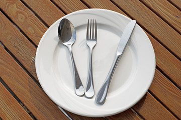 spoon fork and knife on empty white plate