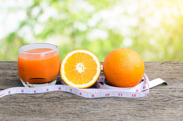 Closeup of measuring tape and oranges  on a wooden floor  at a symbol of diet.