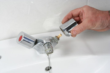 Plumber repairing a faucet in a bathroom