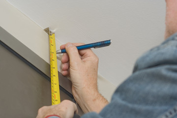 Repairman taking measurements for a curtain rail