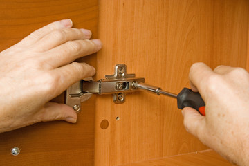Carpenter adjusting a cabinet door hinge