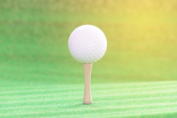 Golf ball with tee on artificial grass.