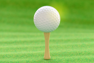 Golf ball with tee on artificial grass.