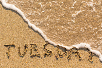 Fototapeta na wymiar Tuesday - drawn of the hand on the beach sand, soft surf wave.