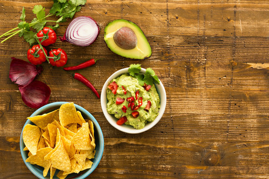 Guacamole with avocado and tomatoes mexican food. wooden background