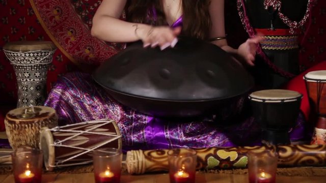 Young adult woman playing hand pan during meditation session
