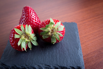 Home rustic strawberry on stone slate plate on wooden background