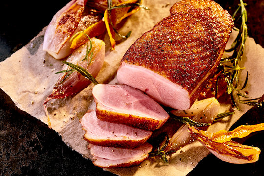 Paper with cooked sliced duck breast and rosemary