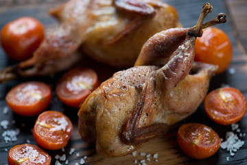 Close-up of whole baked quails and tomatoes, selective focus
