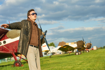 Outdoor fashion shot of male model posing with vintage old propeller plane
