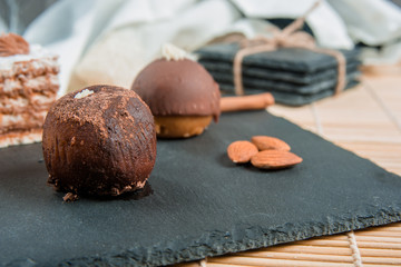 Homemade cookies with nuts, chocolate, caramel and cinnamon on a bamboo mat and on stone slate plate on wooden background