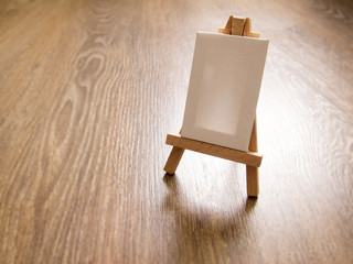 Miniature blank easel on wooden background