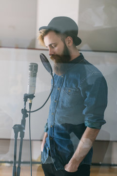 Hipster man singing in a studio