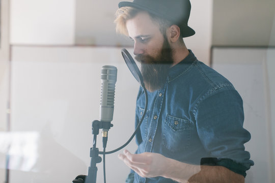 Hipster man singing in a studio