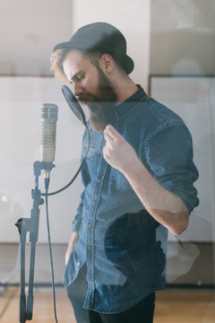 Hipster man singing in a studio