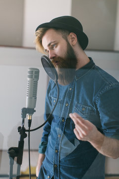 Hipster man singing in a studio