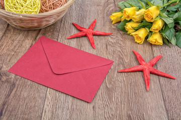 Envelope, starfishes and roses on a wooden background