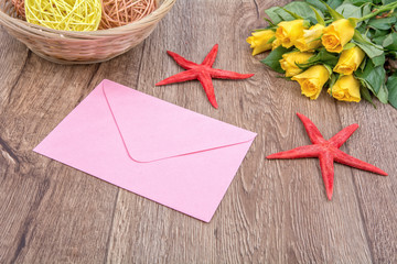 Envelope, starfishes and roses on a wooden background