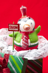 close-up shot of penguin with placard on christmas gift box over red background.