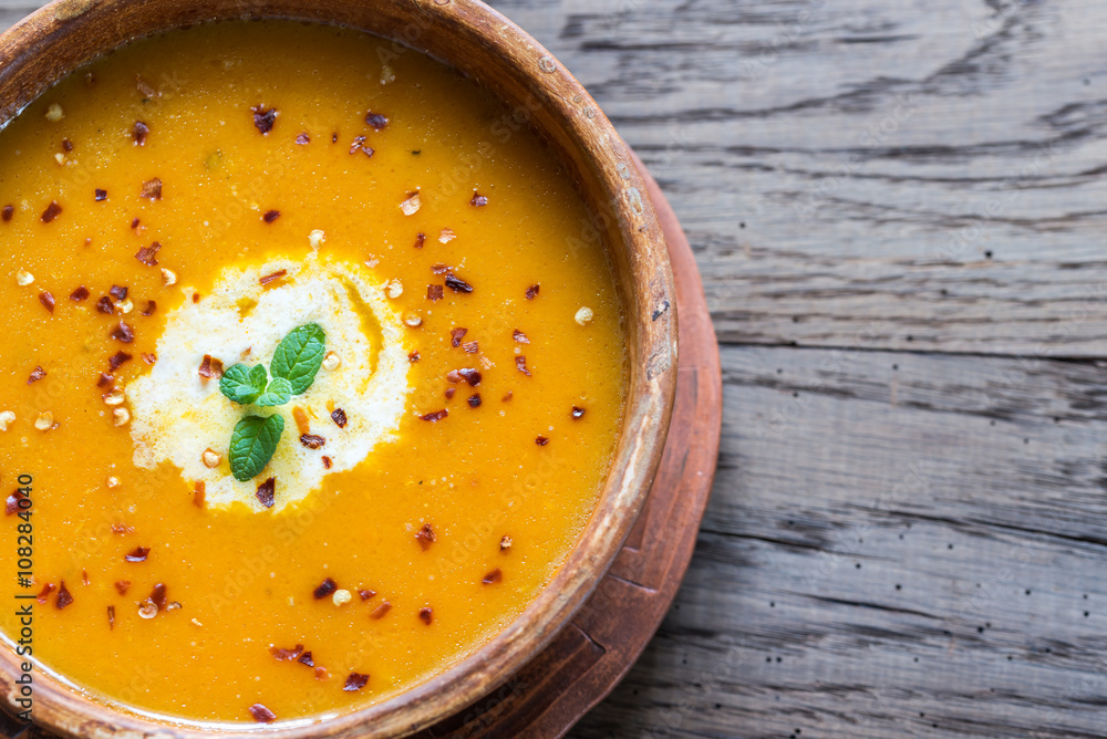 Sticker Bowl of spicy pumpkin cream soup on the wooden table