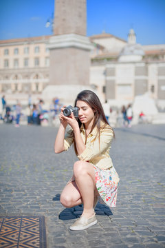 Young tourist woman taking picture with vintage camera in the city