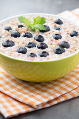 Buckwheat porridge in a bowl with mint leaves and blueberries.