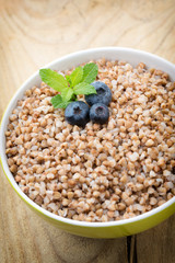 Buckwheat porridge in a bowl with mint leaves and blueberries.