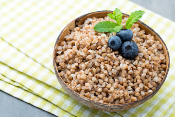 Buckwheat porridge in a bowl with mint leaves and blueberries.