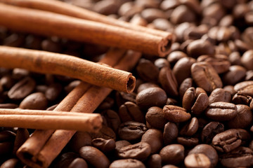 Cinnamon sticks laying above brown coffee beans