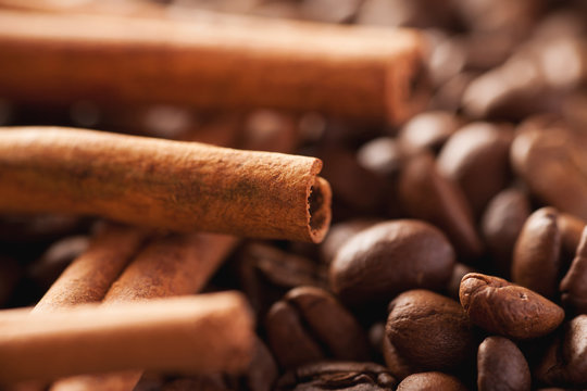 Cinnamon sticks laying above brown coffee beans