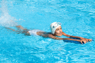 femme pratiquant la natation dans une piscine avec une planche et un masque