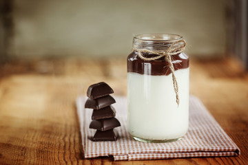 Milk yoghurt with chocolate tower on a wooden background, simple
