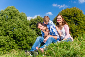 Fototapeta premium Family having fun sitting in the green grass
