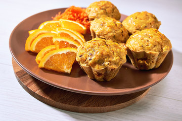 Carotte muffins served on the plate with orange slices.