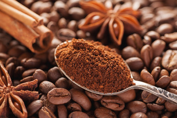 Grounded coffee in silver spoon with cinnamon and star anise