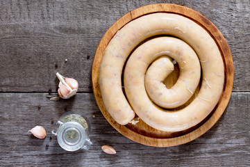 Homemade sausage with potatoes and bacon on dark wooden board