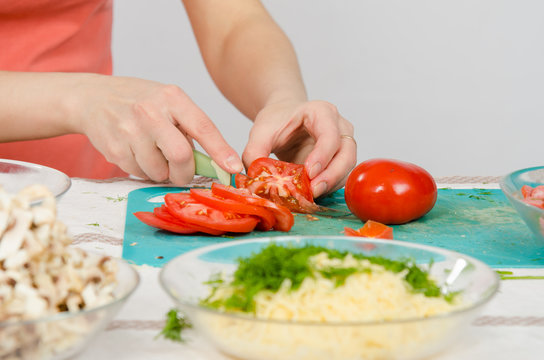 Close-up of female hands cutting tomato on kitchen table