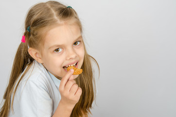 Portrait of a little six year old girl biting a cookie