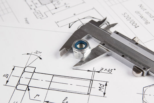 Caliper and nuts on a background of engineering drawings. Science, mechanics and mechanical engineering.