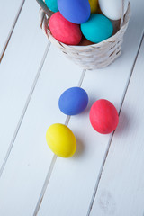 Easter eggs in the basket on wooden boards on a white background. Close up