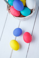 Easter eggs in the basket on wooden boards on a white background. Close up. Vertical shot